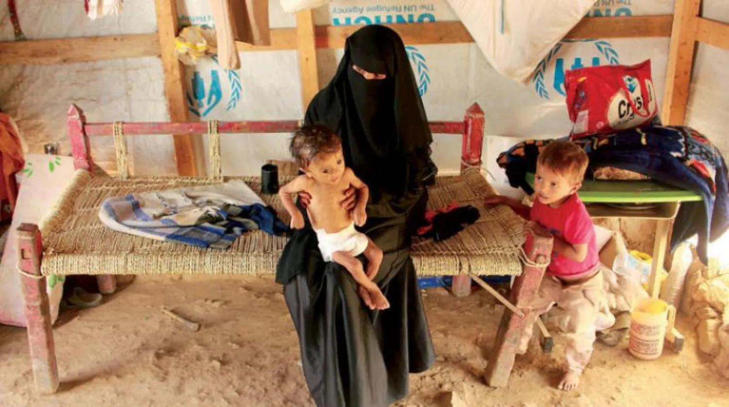 A Yemeni woman and her two children in a camp for the displaced in Hajjah governorate (AFP)