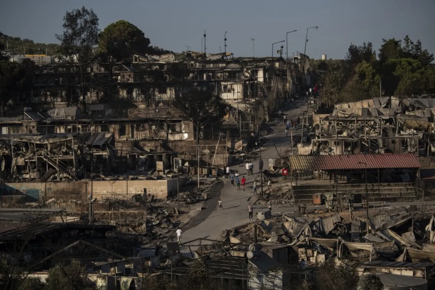 Migrants walk at the burned Moria refugee after a fire, on the northeastern Aegean island of Lesbos, Greece, on Wednesday, Sept. 9, 2020 (AP Photo/Petros Giannakouris)
