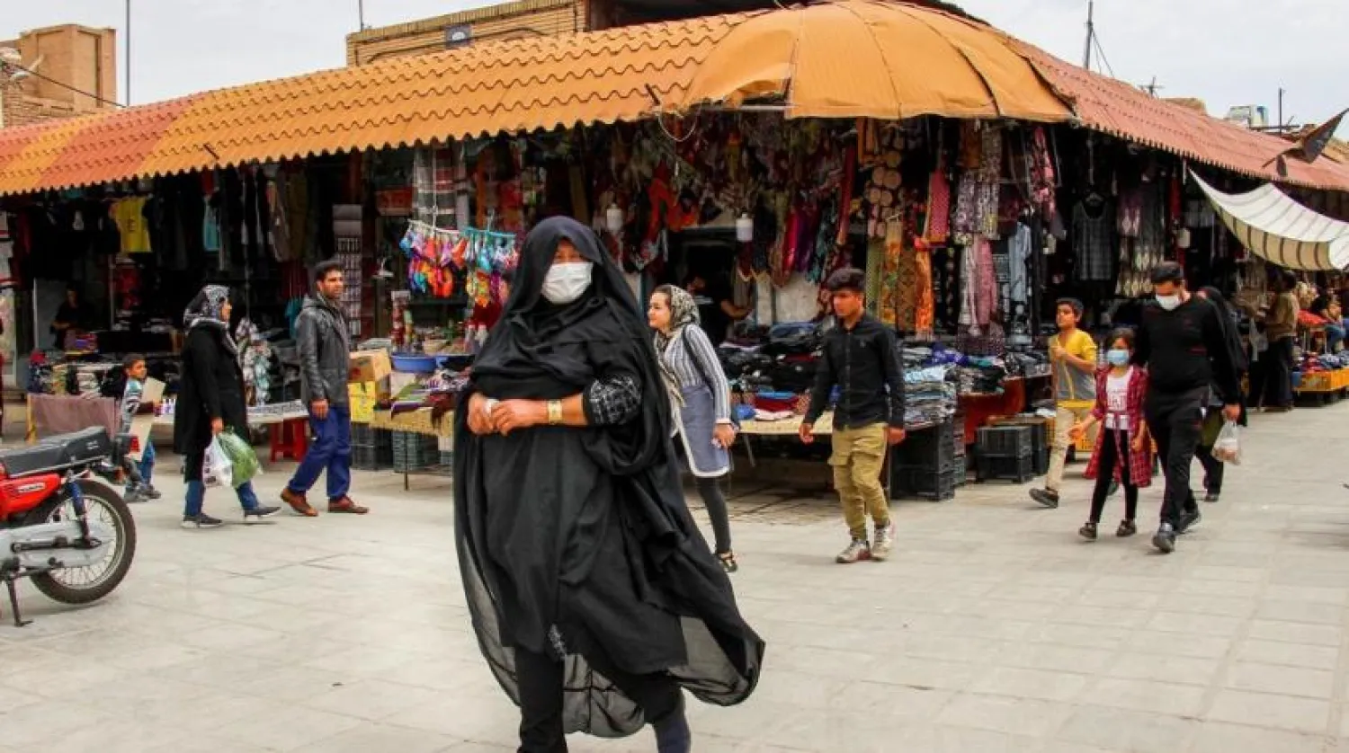Iranians, some wearing face masks, walk past shops in the southeastern city of Kerman. (AFP)
