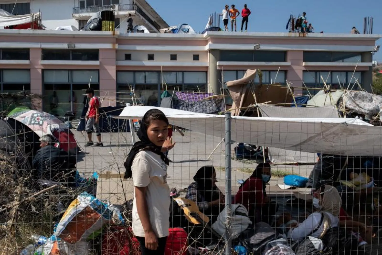 لاجئون ومهاجرون من مخيم موريا المدمّر بالقرب من مخيم مؤقت في جزيرة ليسبوس اليونانية (رويترز)