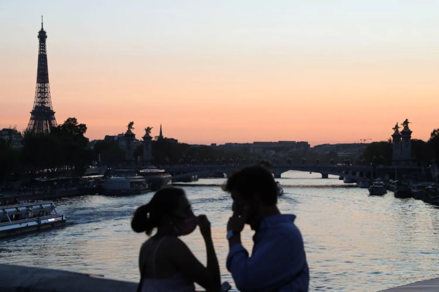 رجل وامراة يشاهدان غروب الشمس في باريس (أ.ف.ب)