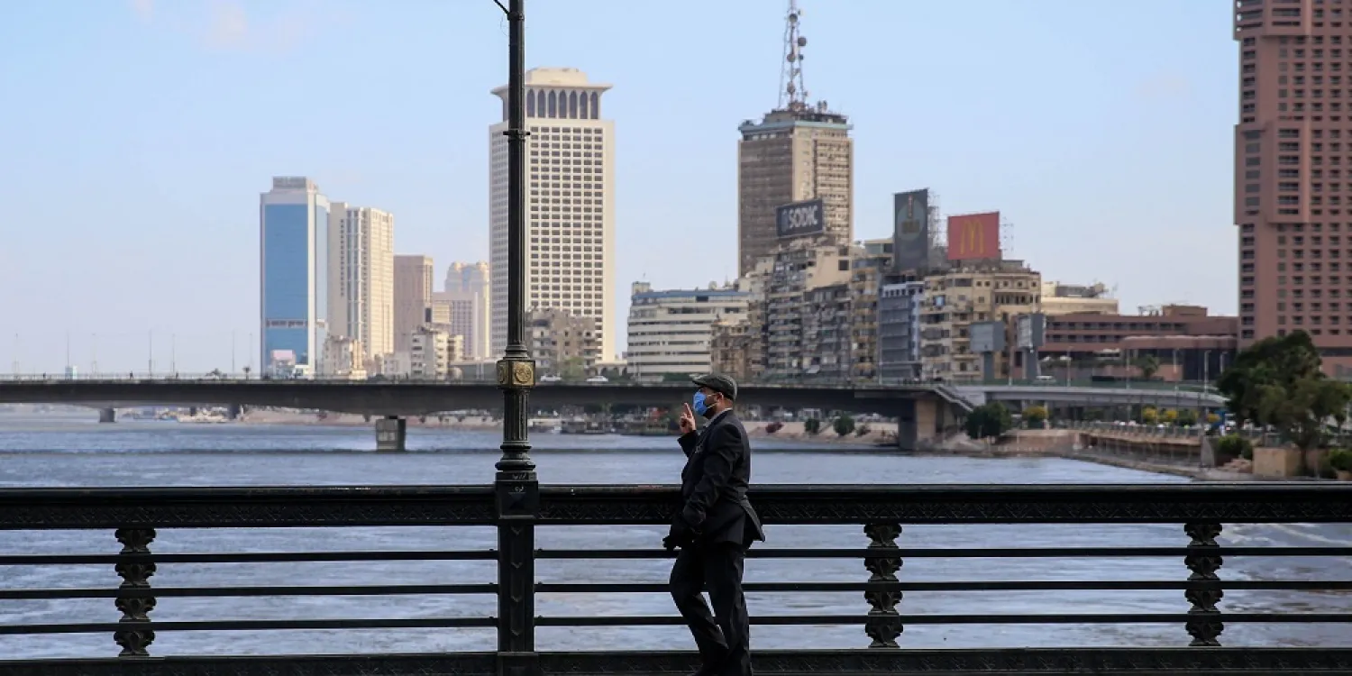 A mask-clad man walks along the Kasr el-Nil bridge connecting the island district of Zamalek to the city center of Cairo, May 24, 2020. (AFP)