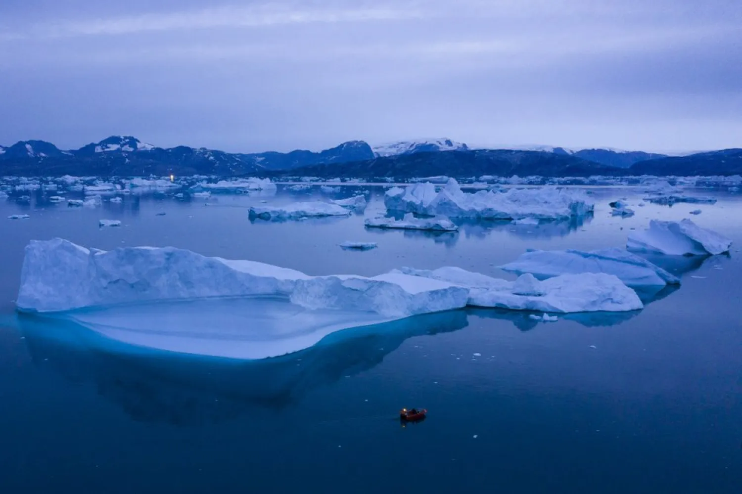 In this Aug. 15, 2019, photo, a boat navigates at night next to large icebergs near the town of Kulusuk, in eastern Greenland. (AP)