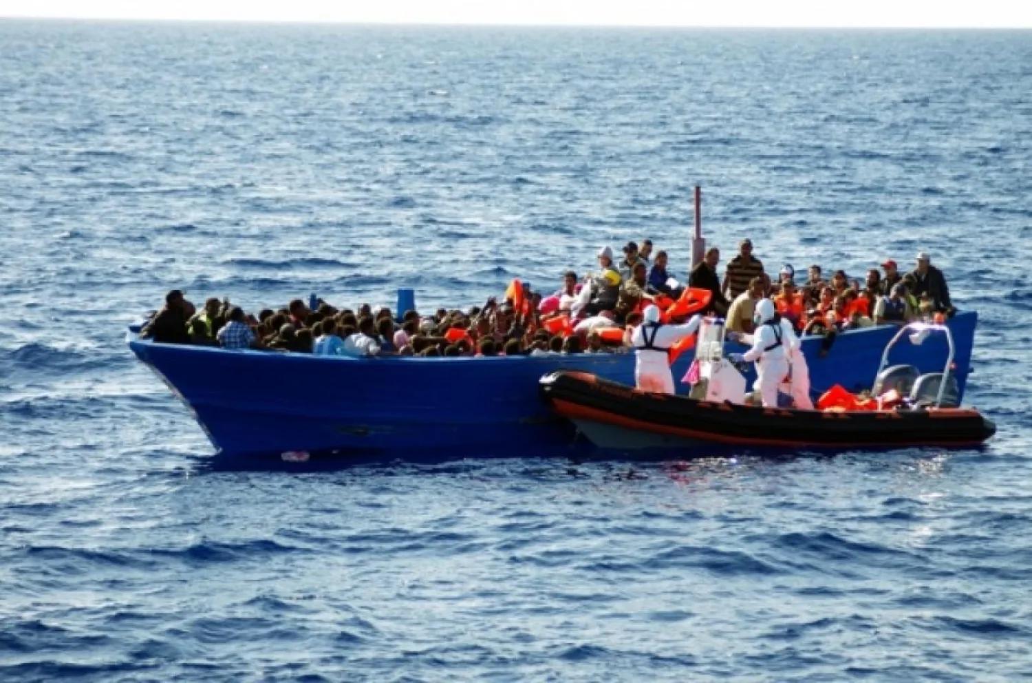 Rescuers of the MOAS's ship Phoenix helping shipwrecked migrants to climb on their boat (AFP)
