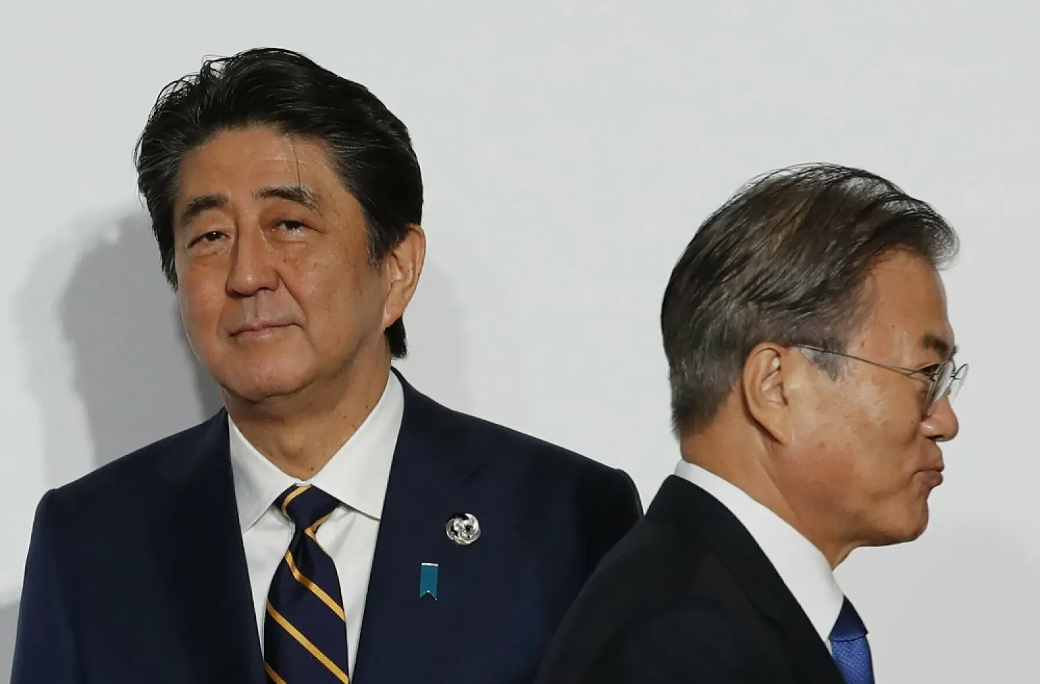 South Korean President Moon Jae-in, right, walks by Japanese PM Shinzo Abe upon his arrival for a welcome and family photo session at the G20 leaders summit in Osaka, Japan, June 28, 2019. (AP)