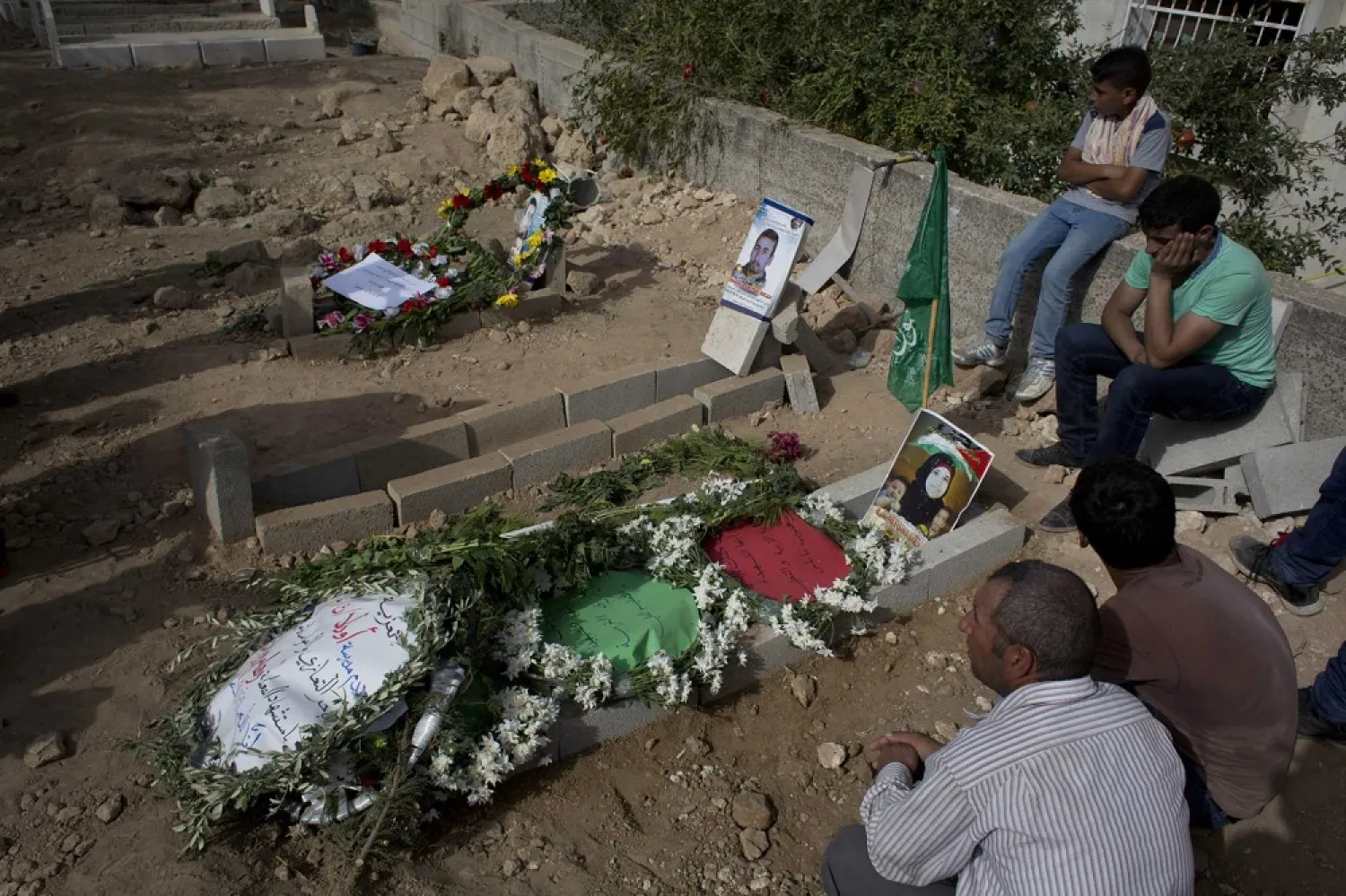 In this Sept. 7, 2015 file photo, Palestinians mourn at the graves of Riham Dawabsheh, 27, her husband Saed Dawabsheh and their 18-month-old son Ali, in the West Bank village of Duma, near Nablus. (AP)