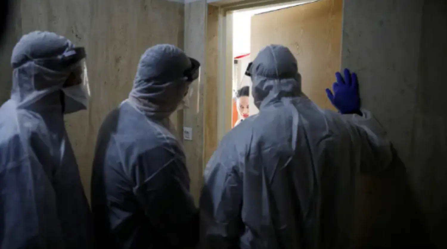 Health Ministry inspectors speak with a woman who is in self quarantine as a precaution against coronavirus spread in Hadera, Israel March 16, 2020 (photo credit: REUTERS/RONEN ZEVULUN)
