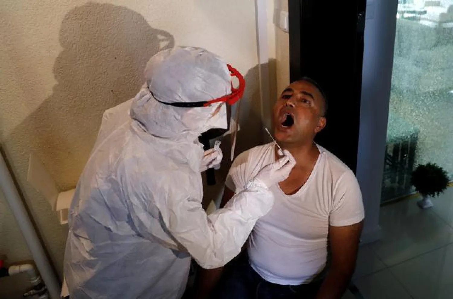FILE PHOTO: A medical worker of the Bakirkoy District Health Directorate wearing a protective suit takes a swab sample from Mustafa Unlu during an antibody testing program following the coronavirus disease (COVID-19) outbreak, in Istanbul, Turkey, June 17, 2020. REUTERS/Murad Sezer/File Photo