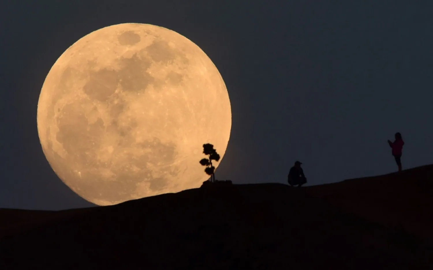 In this file photo taken on January 30, 2018, a person poses for a photo as the moon rises over Griffith Park in Los Angeles, California. (AFP)