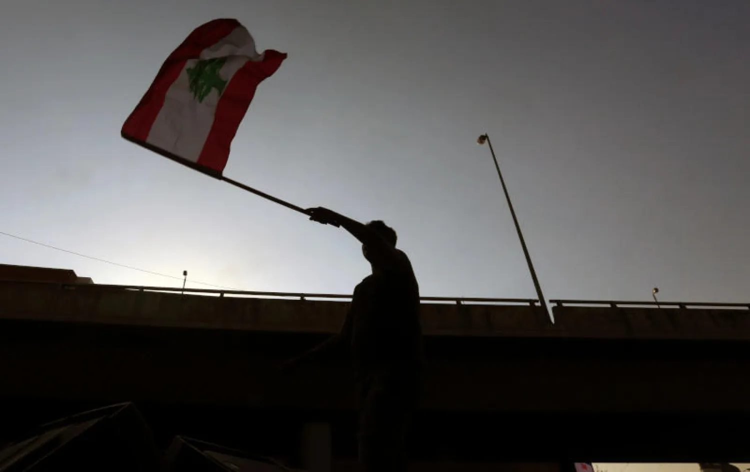 متظاهر يلوح بعلم لبنان خلال احتجاجات مناهضة للحكومة قرب قصر بعبدا الرئاسي في بيروت (رويترز)