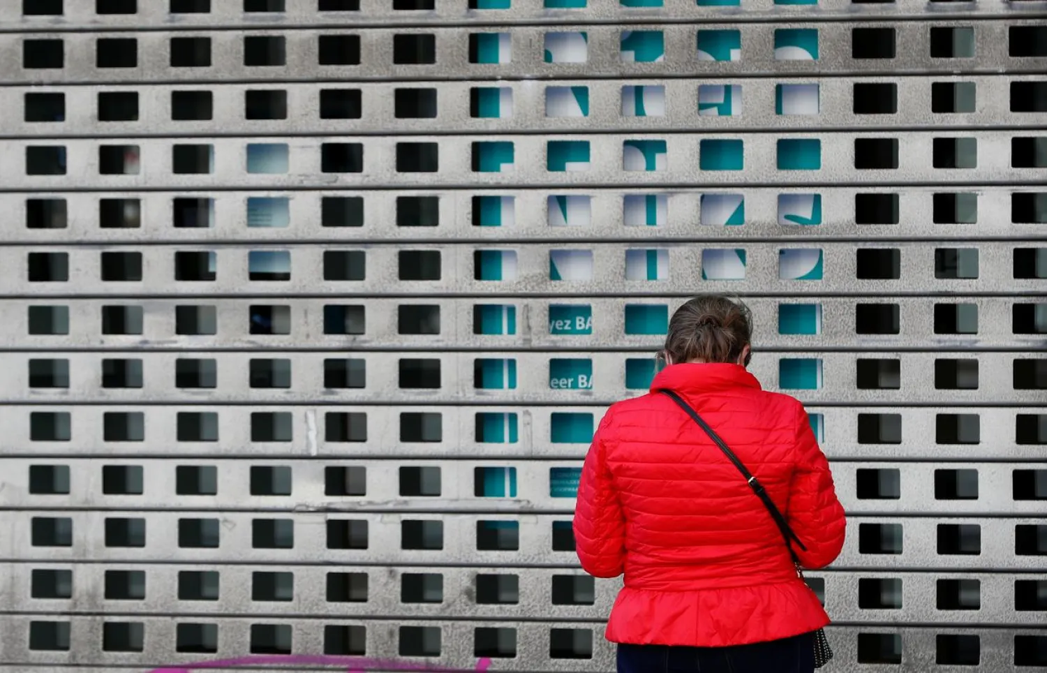 A woman stands in front of a closed store during the lockdown imposed by the Belgian government to slow down the coronavirus disease (COVID-19) spread, in Brussels, Belgium April 24, 2020. REUTERS/Francois Lenoir