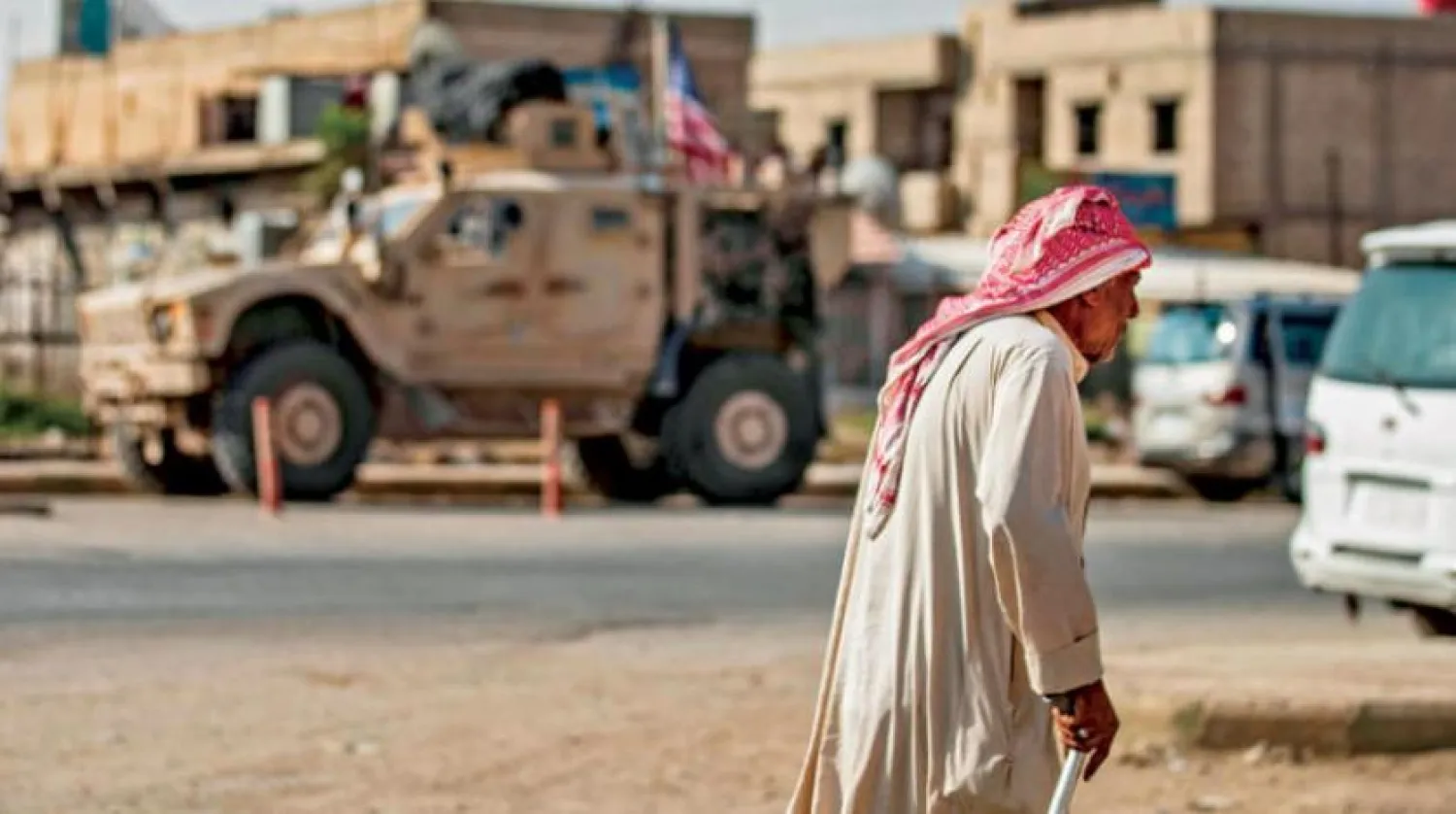 A Syrian man walks by as a US military vehicle patrols the town of Tal Tamr, in Syria's northeastern Hasakeh province, on September 21, 2020. (Photo by Delil SOULEIMAN / AFP)