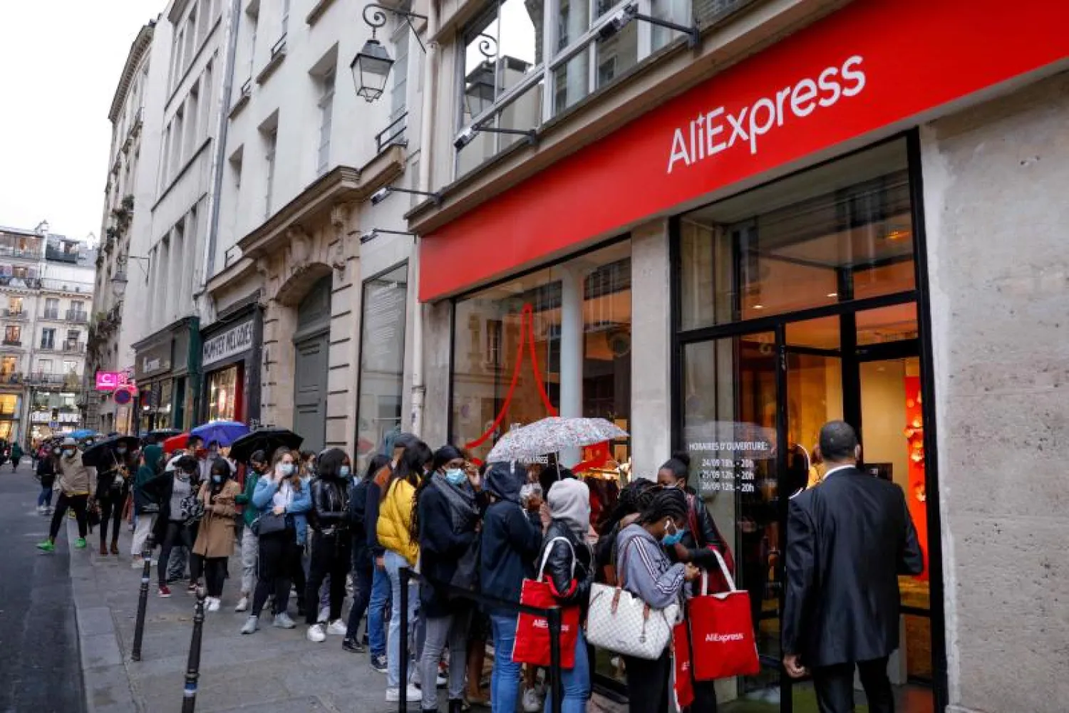 متسوقون يضعون كمامات ينتظرون لدخول متجر في باريس (أ.ف.ب)