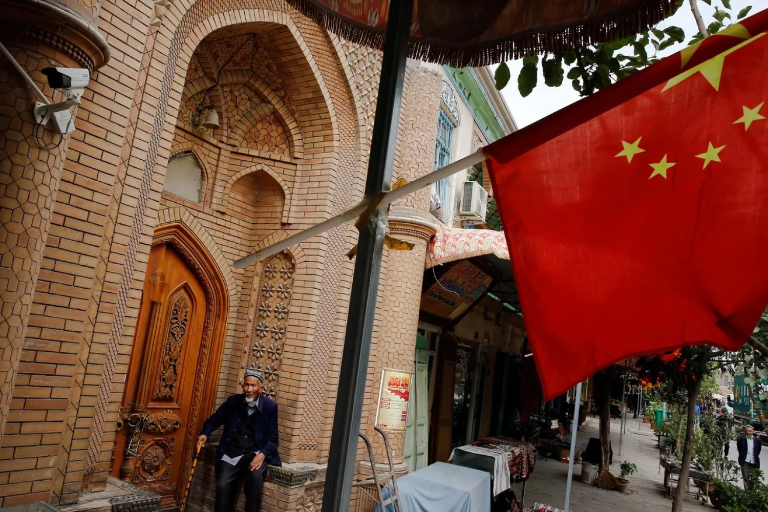 An elderly man is seen behind a Chinese national flag in the Old City in Kashgar in Xinjiang Uighur Autonomous Region, China September 6, 2018. REUTERS/Thomas Peter