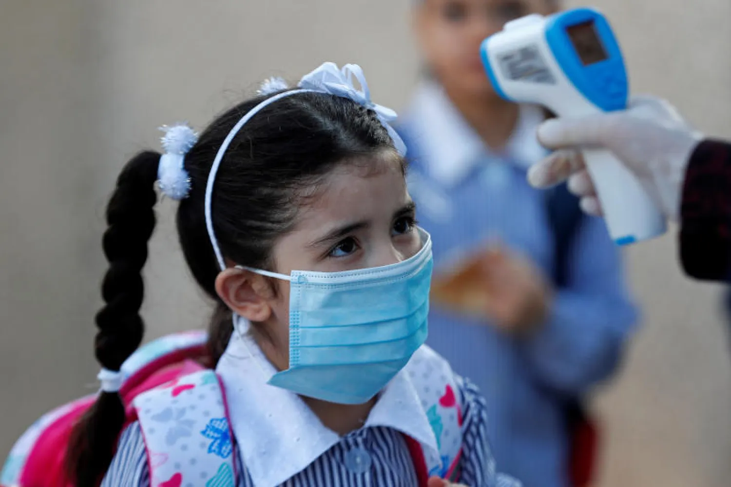 فحص حرارة تلميذة فلسطينية في مدرسة تديرها الأمم المتحدة بمدينة رام الله (رويترز)