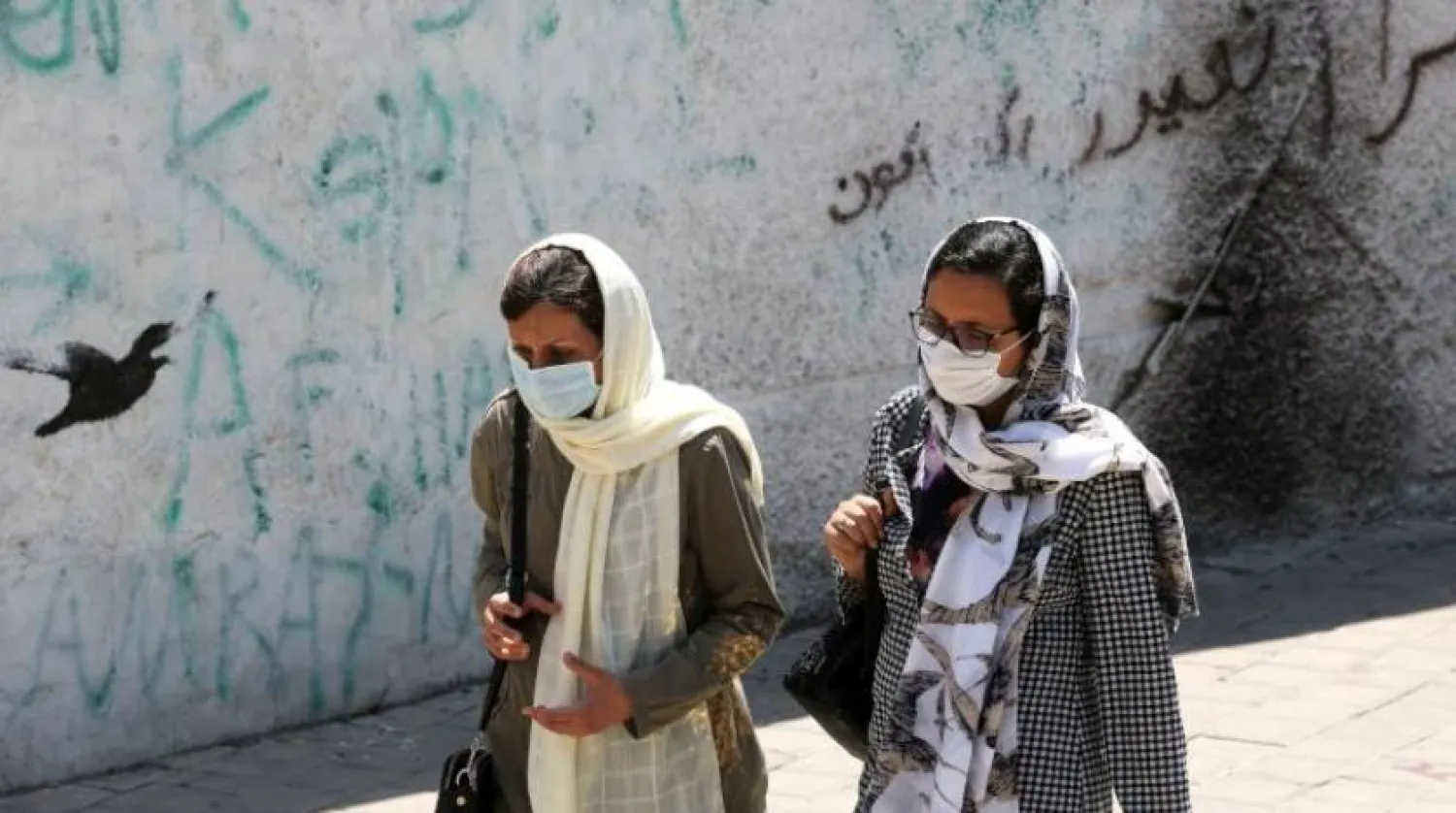 İran'ın başkenti Tahran'da bir sokakta maskeli iki kadın (AFP)