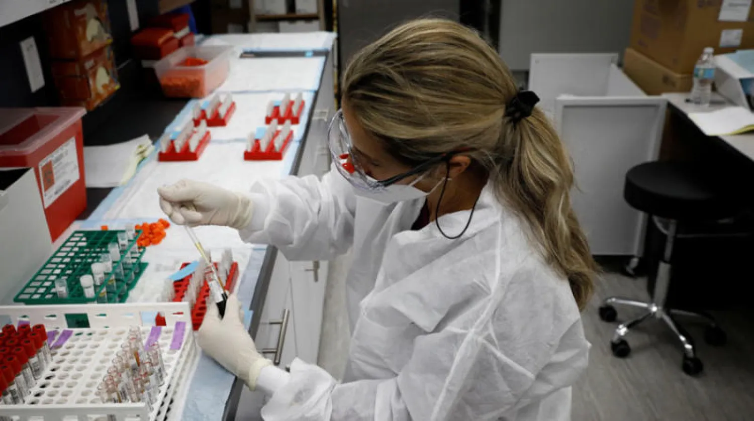 عاملة صحة تفصل البلازما من دم مريض بـ«كورونا» في مختبر بفلوريدا (رويترز)