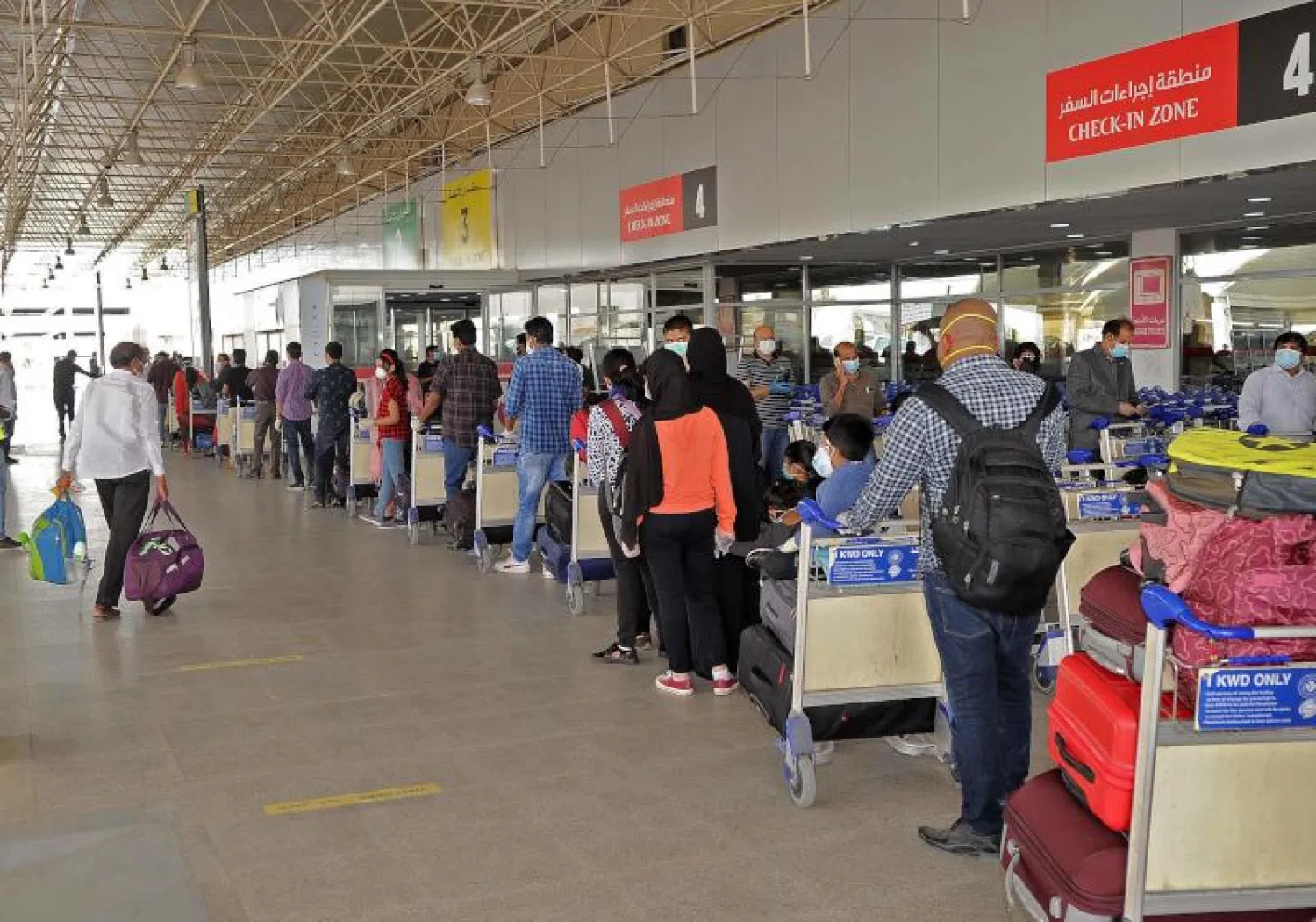 مقيمون هنود يصطفون في طوابير بمطار الكويت الدولي قبل ركوب رحلة العودة إلى بلادهم (أ.ف.ب)