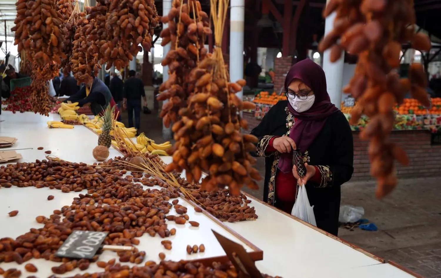 A Tunisian woman sells dates on the first day of Ramadan at a market in Tunis, Tunisia, 24 April 2020. (EPA)