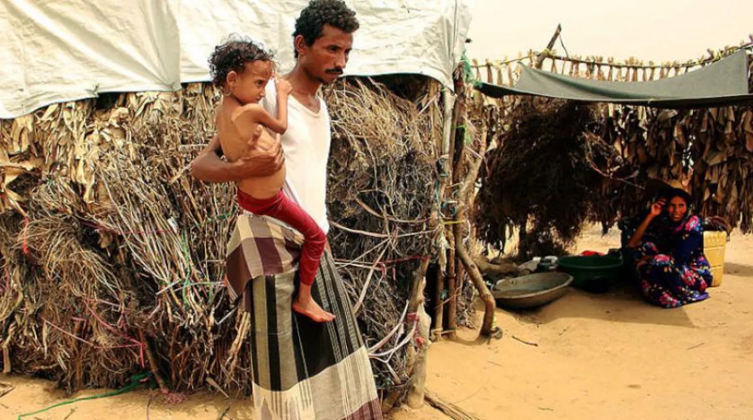 Yemenli bir adam, Hacca kentindeki bir mülteci kampında çocuğuyla birlikte (AFP)