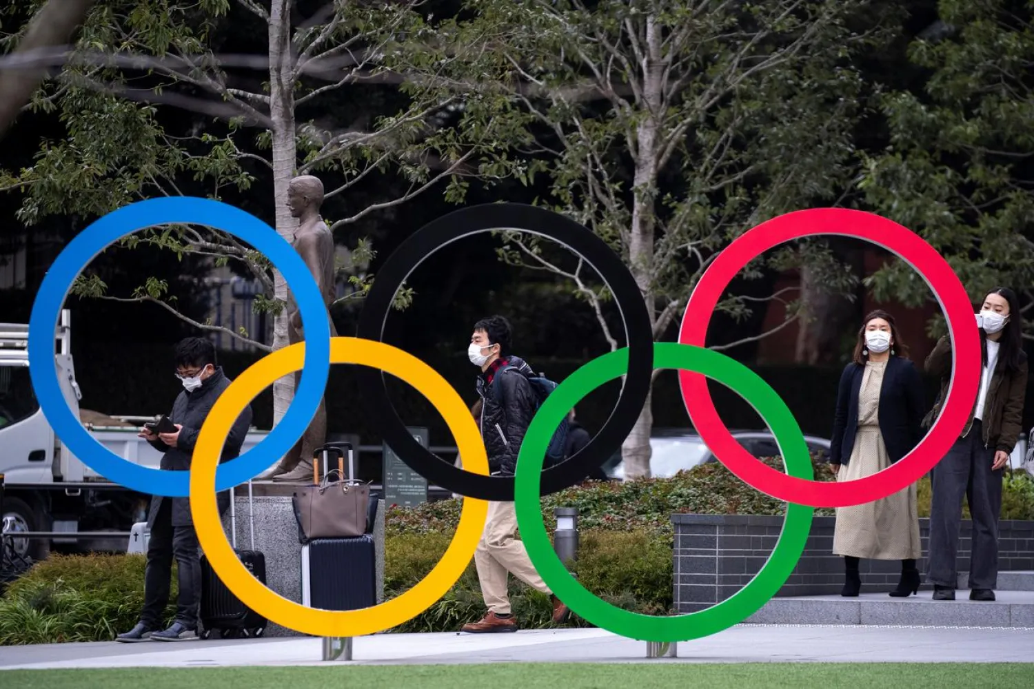 People wearing protective face masks, following an outbreak of the coronavirus, are seen next to the Olympic rings in front of the Japan Olympic Museum in Tokyo, Japan, February 26, 2020. REUTERS/Athit Perawongmetha