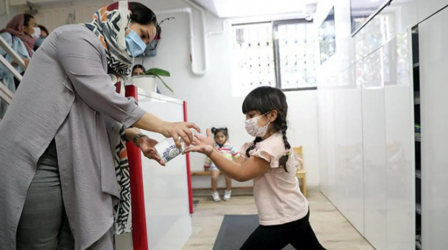 Tahran’da öğrencilerinin ellerini dezenfektan ile temizleyen bir anaokulu öğretmeni. (Reuters)