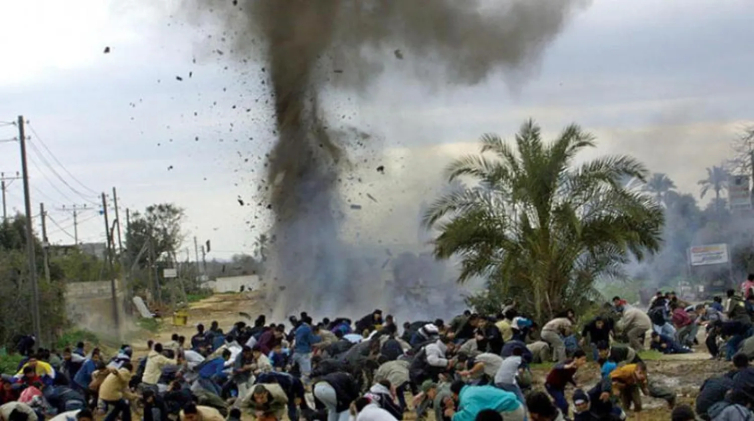 İsrail’in Mart 2004’te düzenlediği saldırılardan korunmaya çalışan Gazze'deki Nuseyrat kampındaki siviller. (AFP)