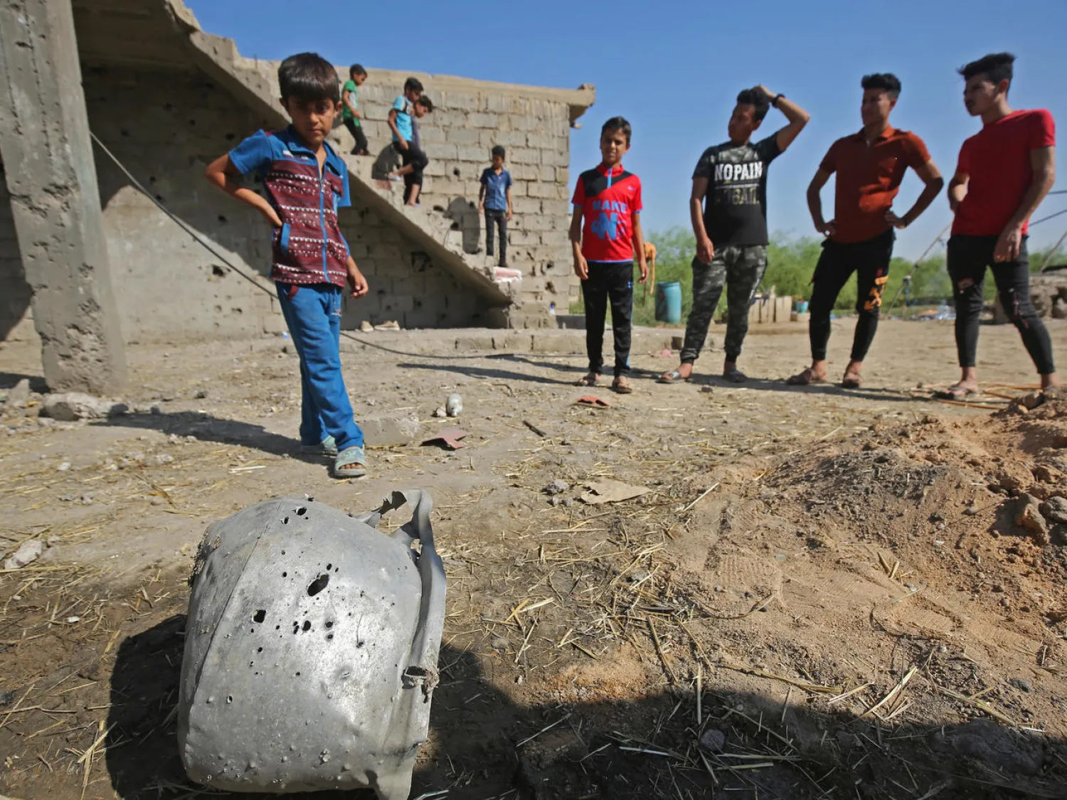 Iraqi youths look at a crater caused by a rocket that killed seven people on Monday night near Baghdad airport AHMAD AL-RUBAYE AFP