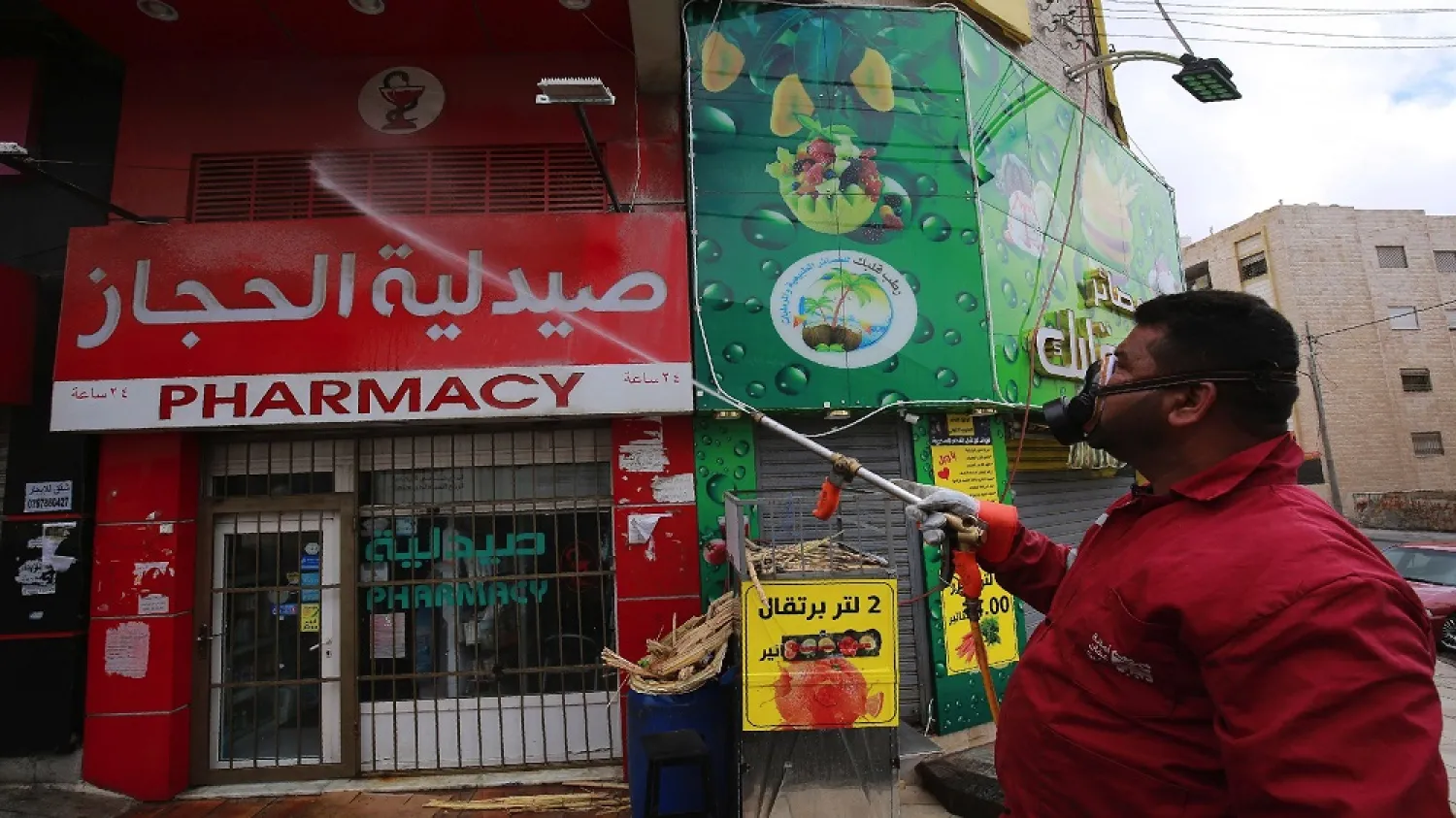 A municipality worker disinfects a pharmacy in the Jordanian capital Amman as part of preventive measures against the spread of the coronavirus, on March 21, 2020. (Getty Images)