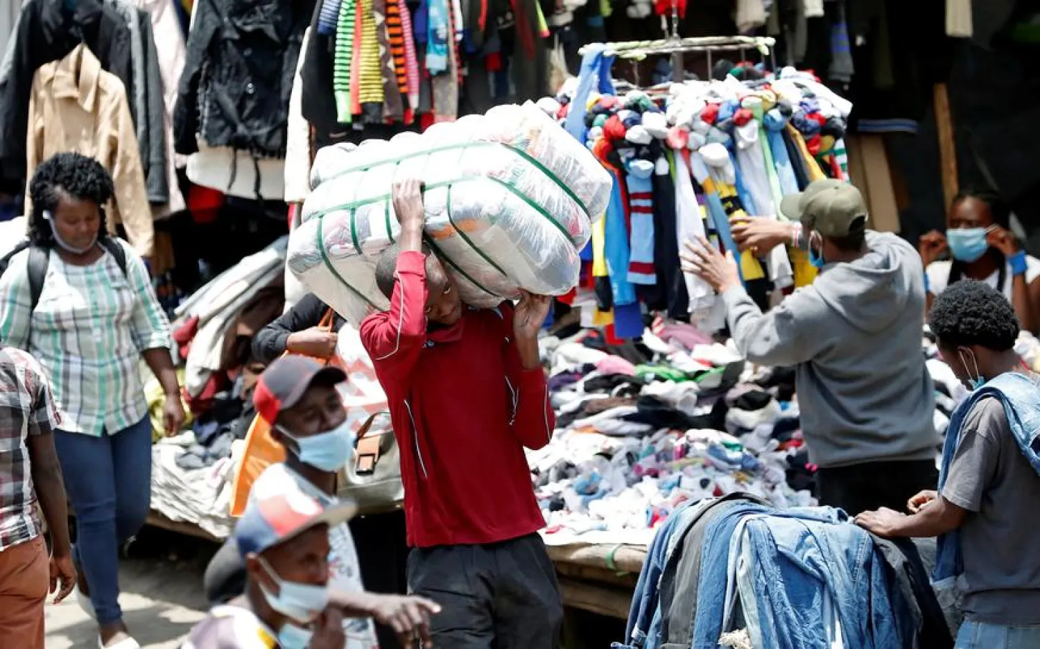 A worker carries a bale of imported second-hand clothes past displayed apparel, amid the coronavirus disease (COVID-19) outbreak at the Gikomba market in Nairobi, Kenya September 18, 2020. REUTERS/Thomas Mukoya