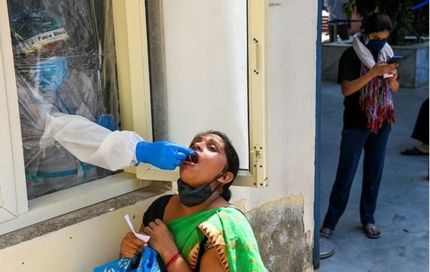 A medical worker collects a swab sample from a woman for a coronavirus test in New Delhi

