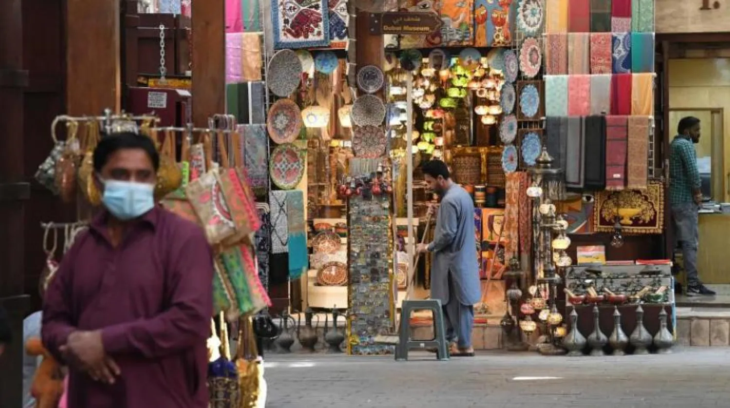 Dubai'de bir pazarda mağazanın önünde duran bir adam salgından korunmak için maske takıyor (AFP)

