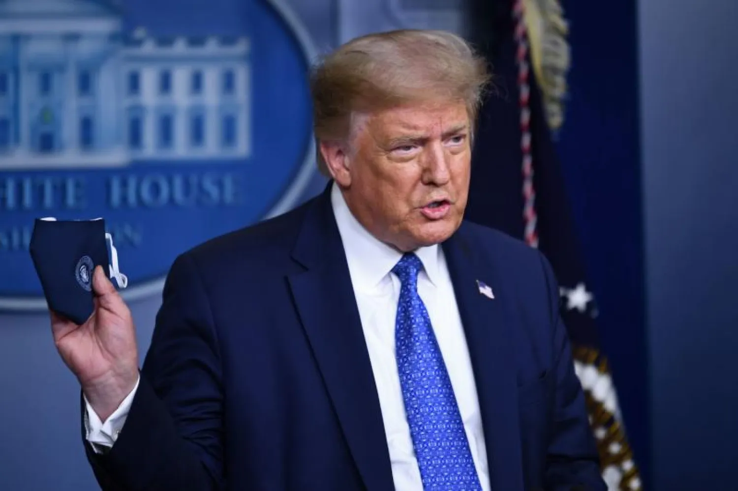 الرئيس الأميركي دونالد ترمب ممسكا بكمامة في البيت الأبيض (أ.ف.ب)