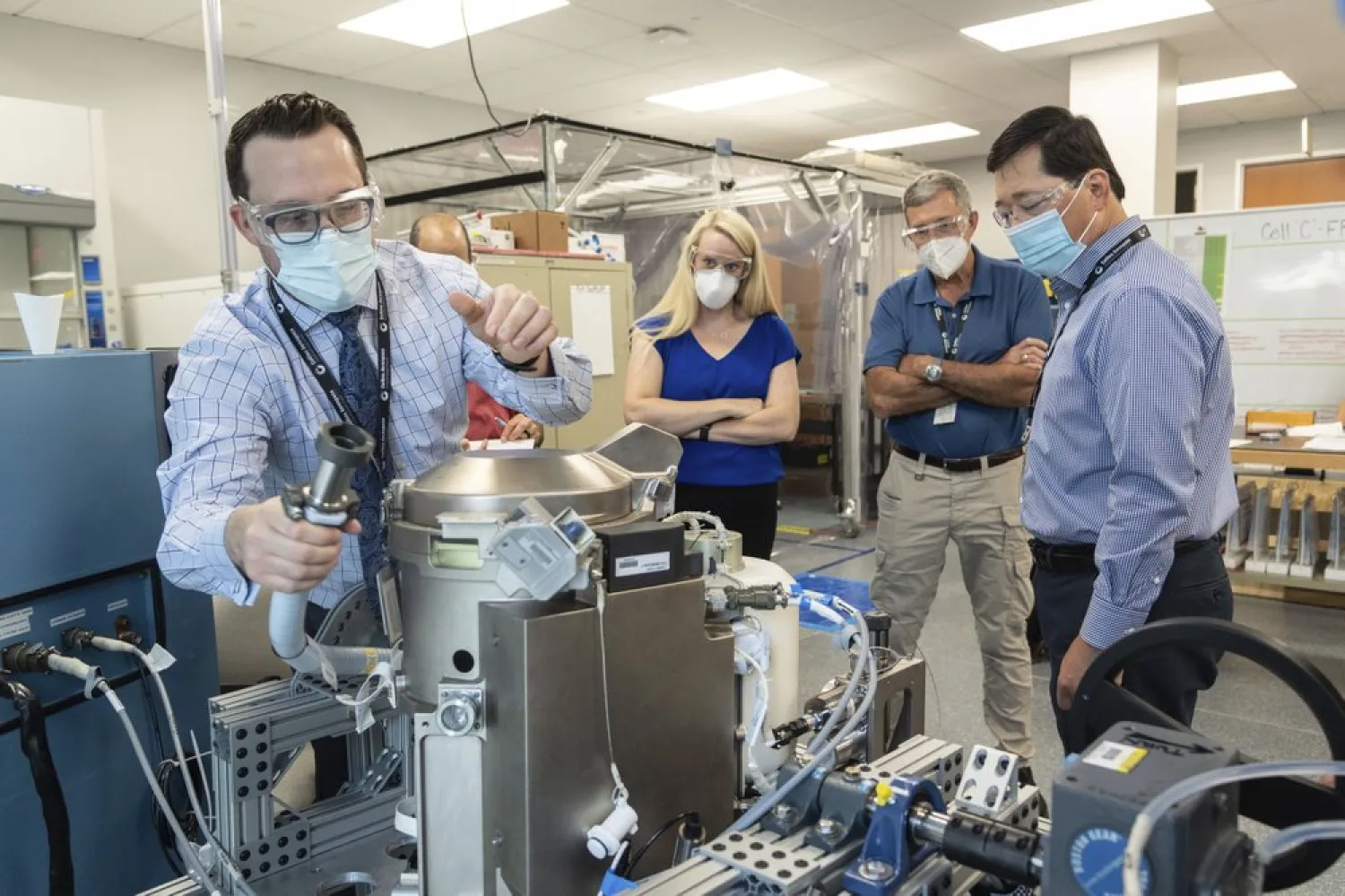 In this June 18, 2020 photo provided by NASA, astronaut Kate Rubins, center, and support personnel review the Universal Waste Management System, a low-gravity space toilet, in Houston. (NASA via AP)