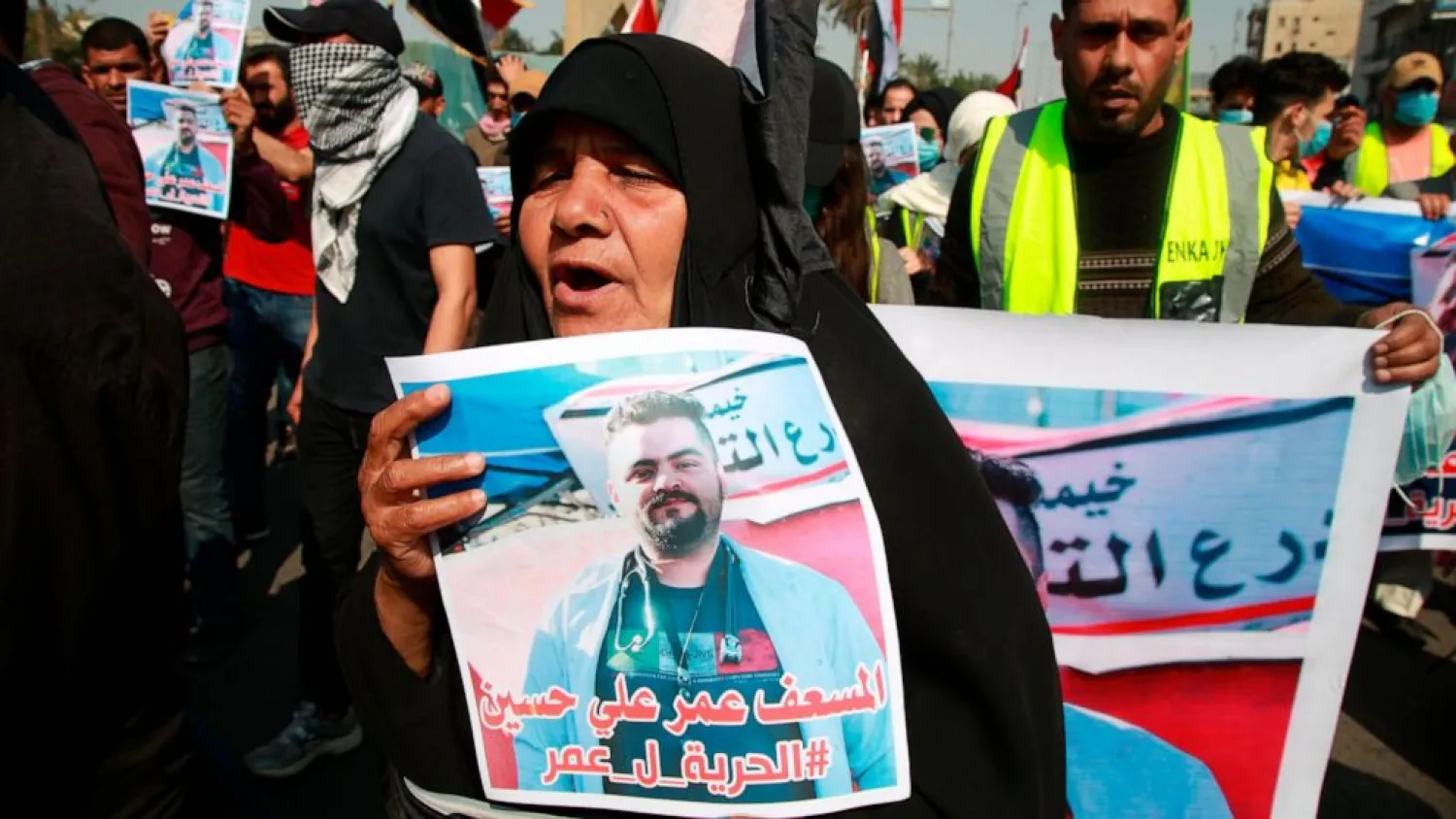 A woman holds a picture of her a missing son during anti-government protest in Baghdad, Iraq, Sunday, Feb. 23, 2020. There are 25 activists still missing since the protests erupted on Oct. 1, 2019, according to the semi-official Iraqi High Commission for Human Rights. No group has claimed responsibility but activists have blamed the militias. Arabic reads, "Freedom for paramedic Omr Ali." (AP Photo/Khalid Mohammed)