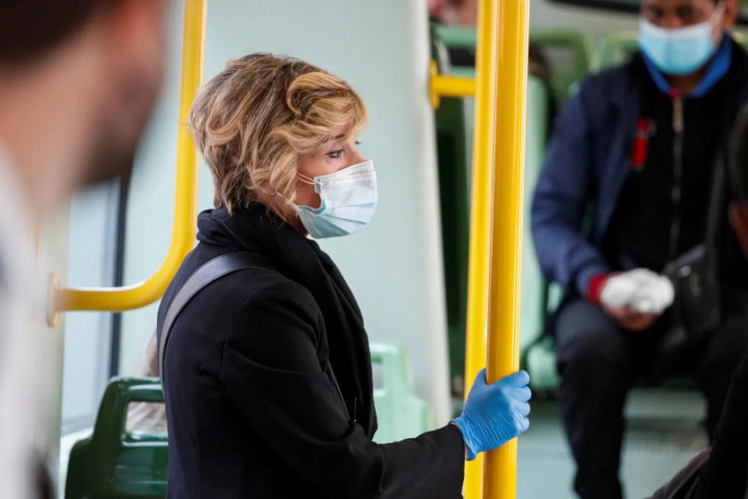 امرأة تضع قناع الوجه الواقي والقفازات خوفاً من كورونا أثناء تنقلها داخل أحد القطارات السريعة في روما (رويترز)