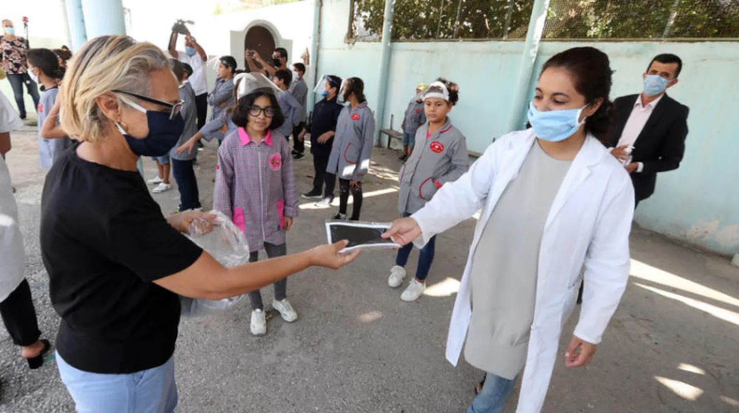 أستاذة تونسية تستعد لتوزيع كمامات واقية في مدرسة بالعاصمة (إ.ب.أ)