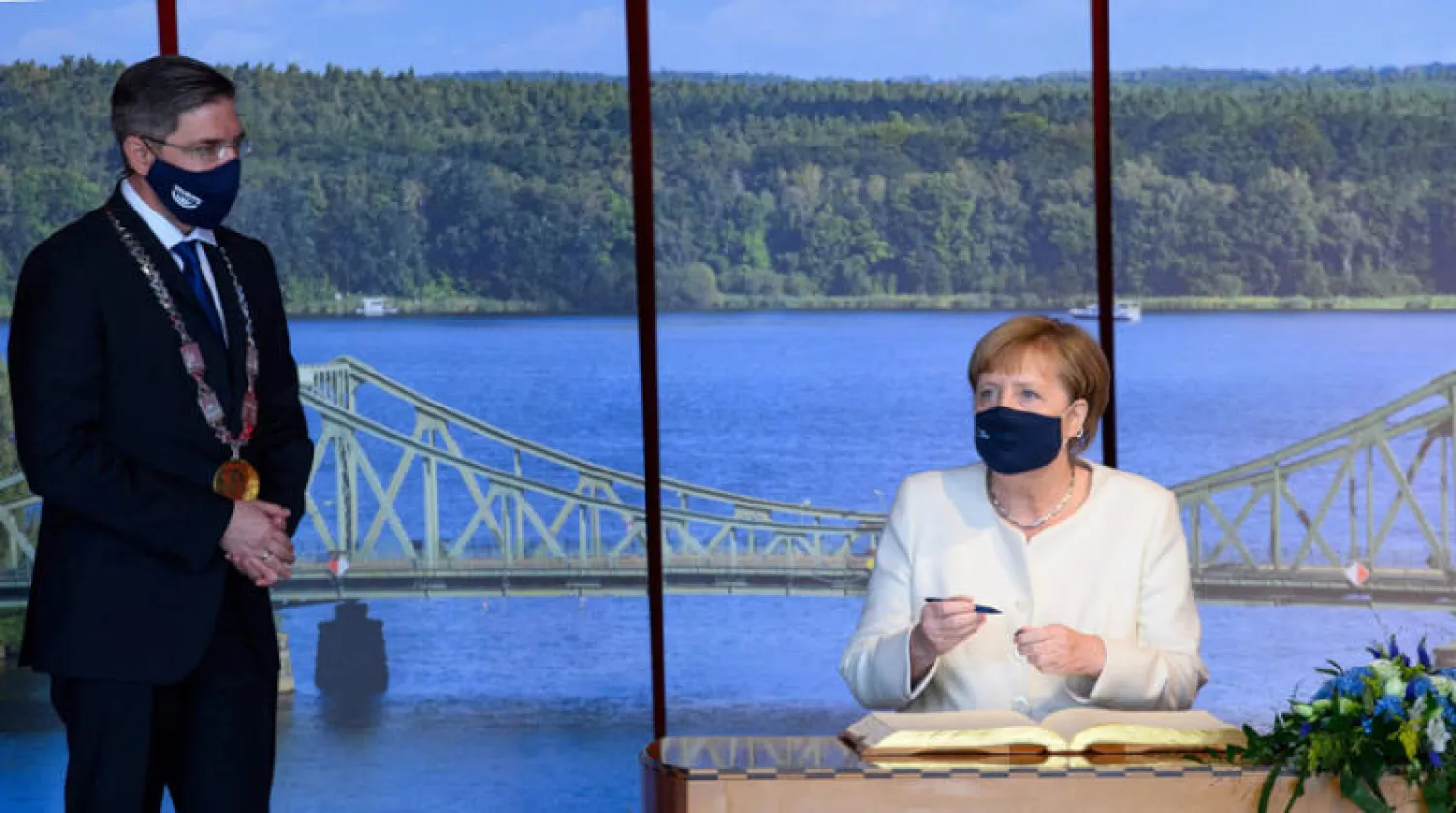 ميركل توقع في الكتاب الذهبي لمدينة بوتسدام خلال الاحتفالات بذكرى 30 سنة على الوحدة الألمانية أمس (أ.ف.ب)