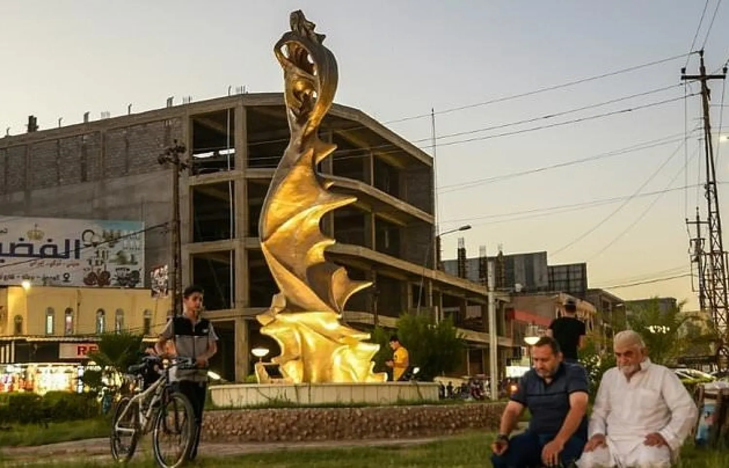 Men pray near the statue of 'My Lovely Lady' erected in the center of a square in Iraq's northern city of Mosul. AFP