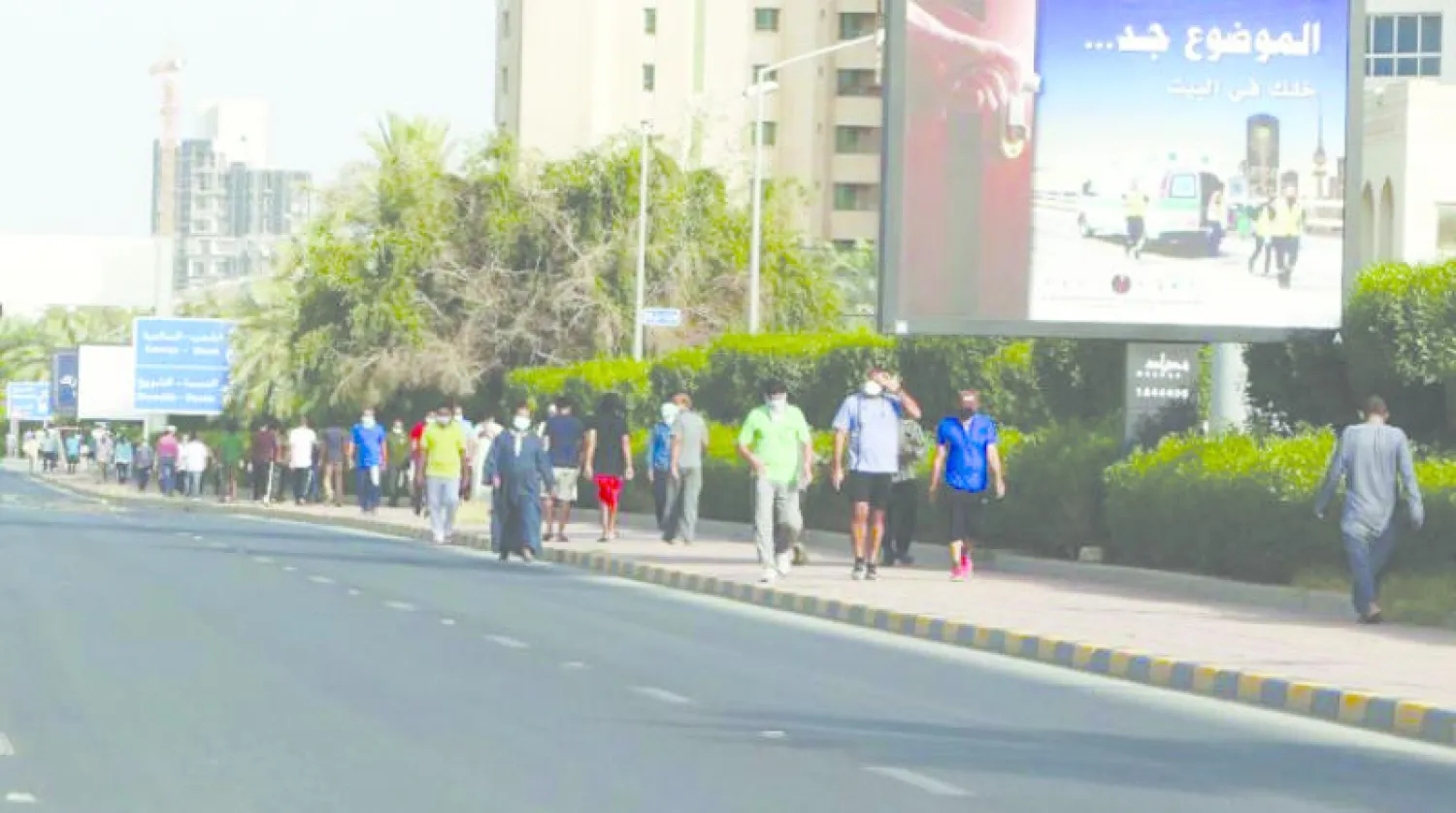 مواطنون ومقيمون يمارسون رياضة المشي في أحد أحياء الكويت العاصمة (أ.ف.ب)