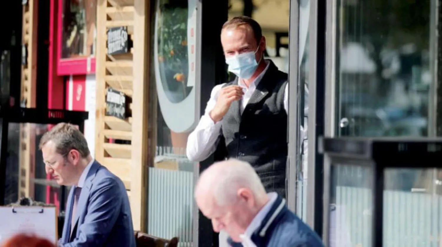 Berlin’de perşembe günü koronavirüs önlemleri kapsamında maske takan bir Alman garson (Reuters)