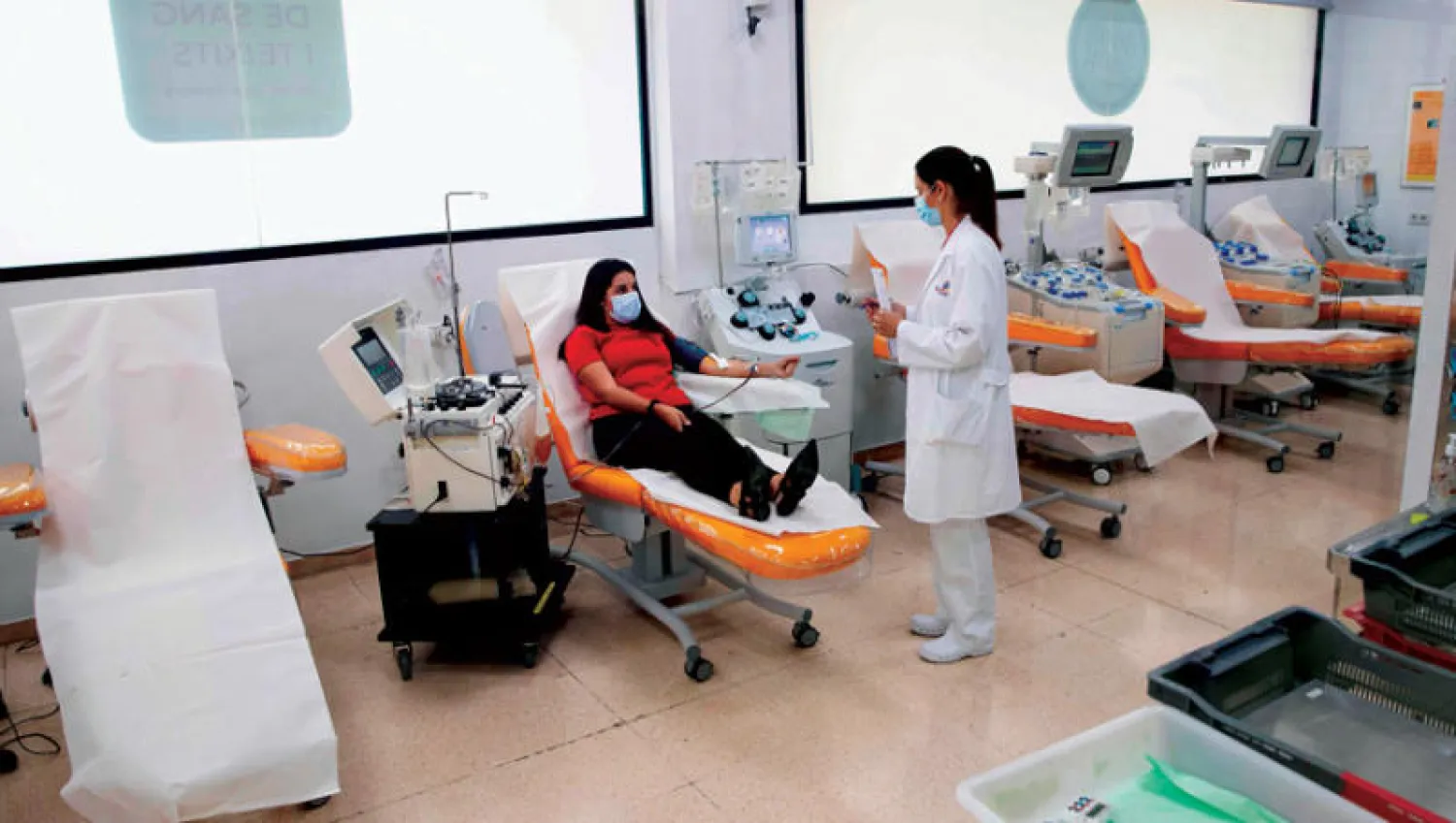 طبيبة تتحدث مع متعافية من {كوفيد - 19} خلال تبرعها ببلازما الدم في إسبانيا أمس (أ.ف.ب)