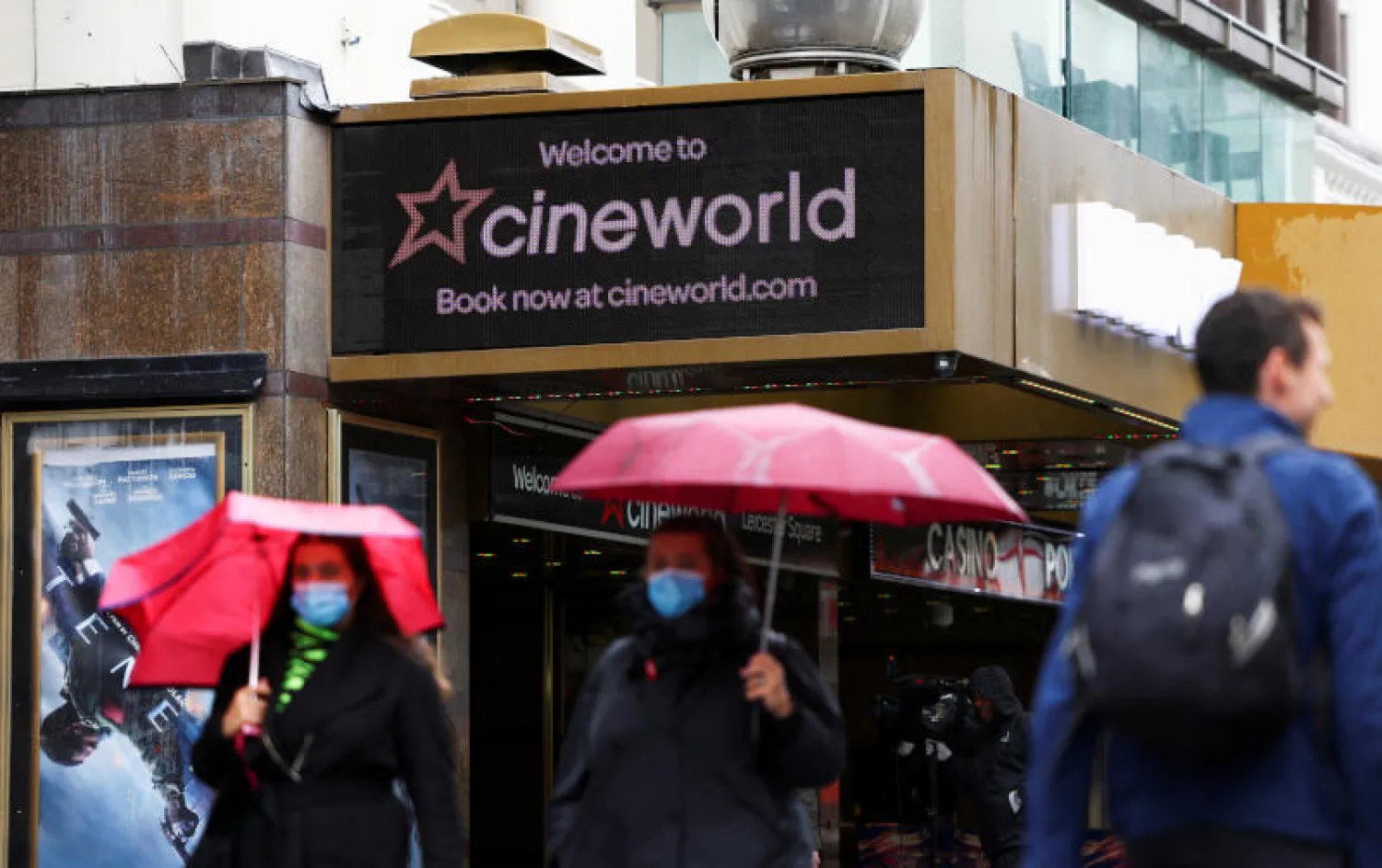 أشخاص يمشون بالقرب من صالة عرض لـ«سينيوورلد» بساحة ليستر في لندن (رويترز)