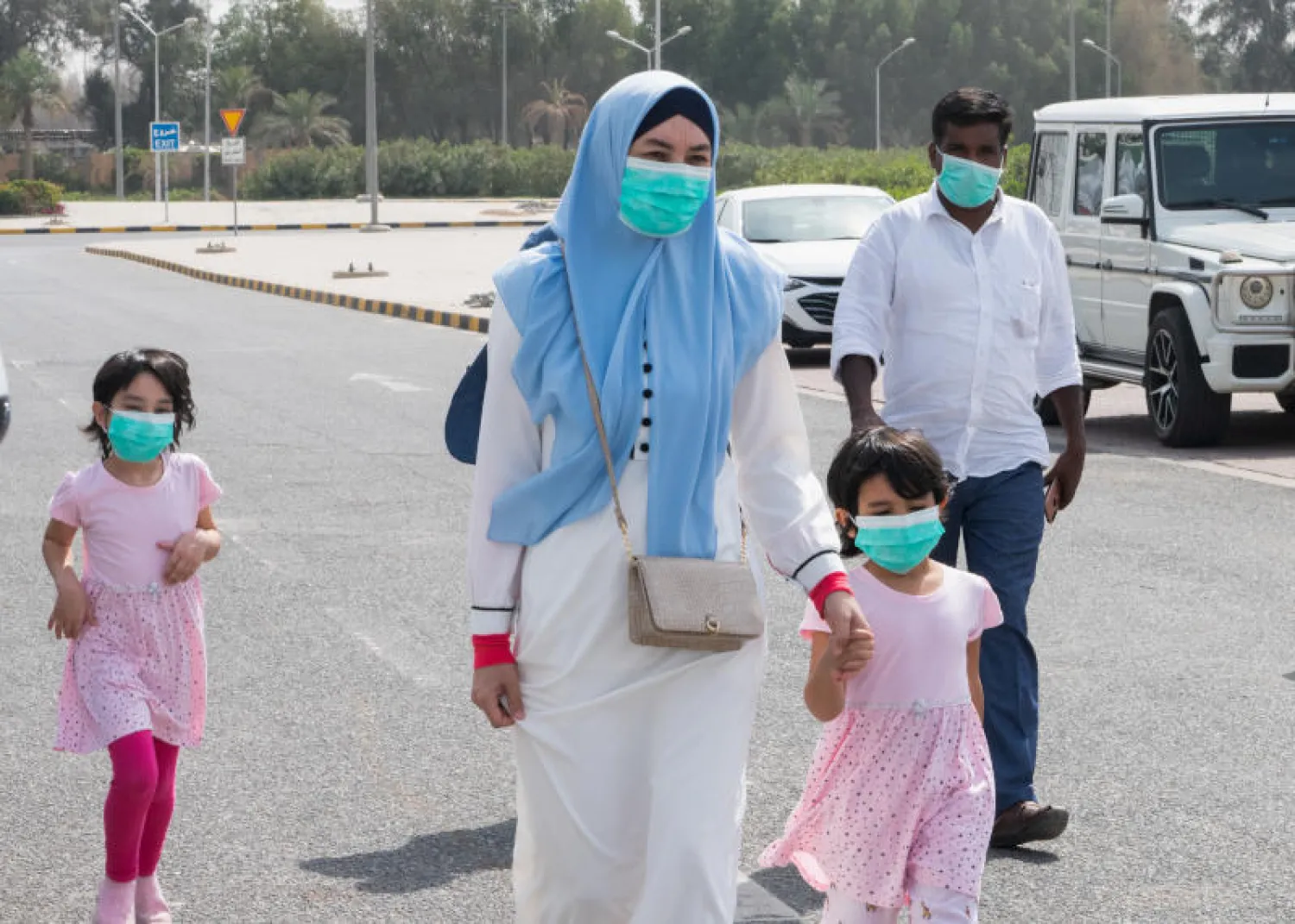 عائلة ترتدي أقنعة واقية في أحد شوارع الكويت العاصمة (أ.ب)