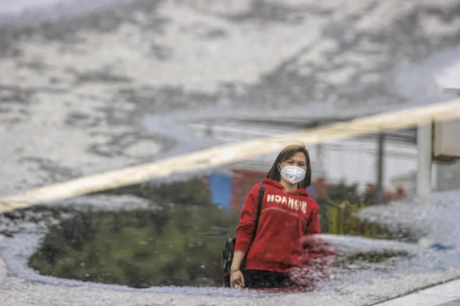 سيدة صينية ترتدي قناعاً واقياً وتمشي في محطة سكة حديد بمدينة قوانغتشو (إ.ب.أ)