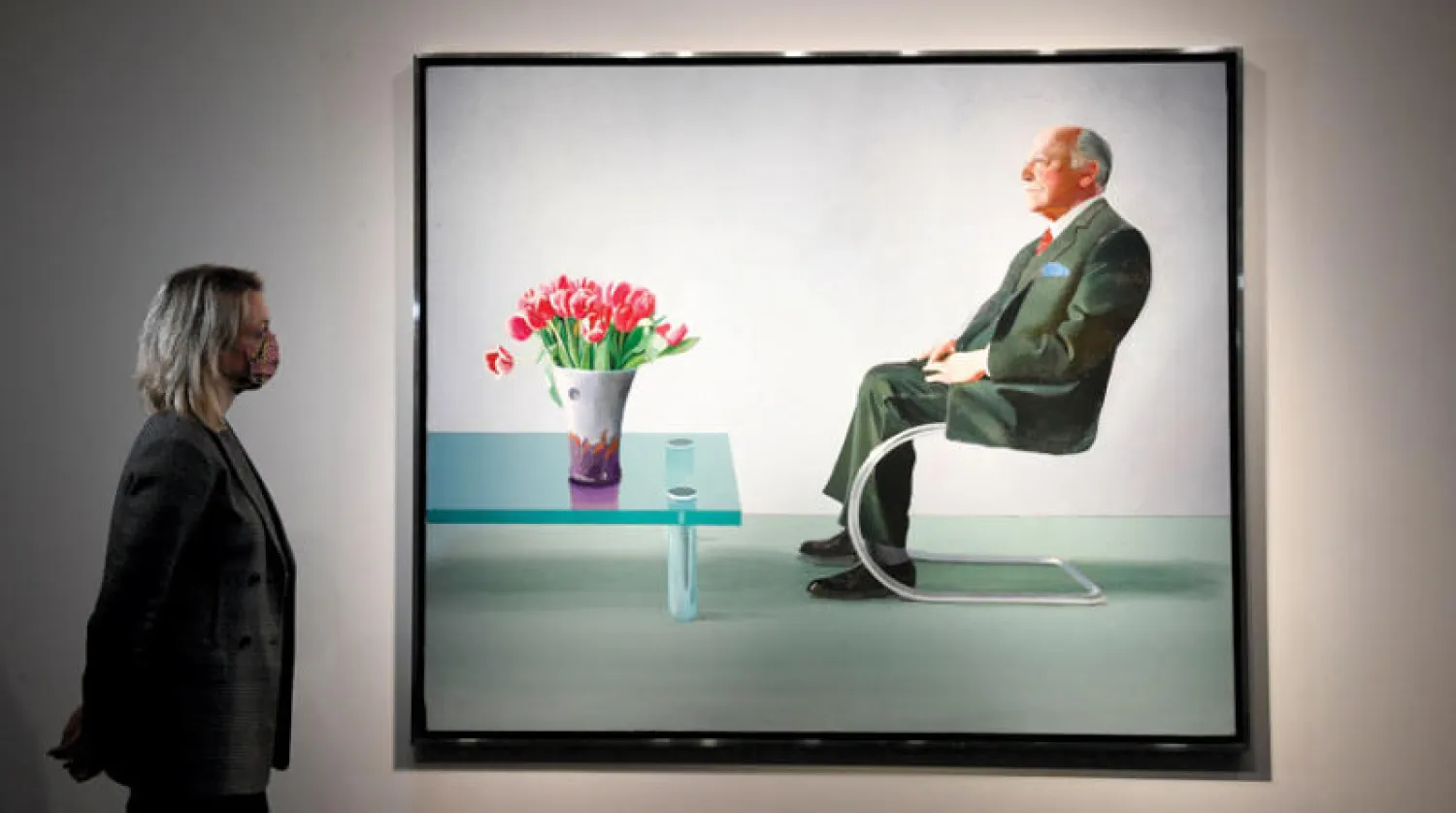 كاثرين أرنولد رئيسة قسم الفن المعاصر بـ«دار كريستيز» أمام لوحة ديفيد هوكني التي تبيعها دار الأوبرا الملكية في المزاد هذا الشهر (رويترز)