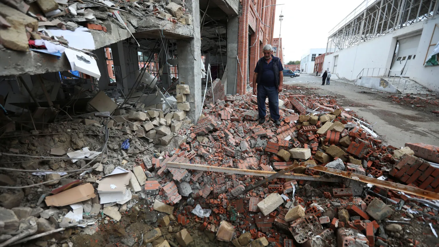A man stands next to a building damaged by recent shelling during a military conflict over the Nagorno-Karabakh region in Ganja, Azerbaijan, October 6, 2020. /Reuters