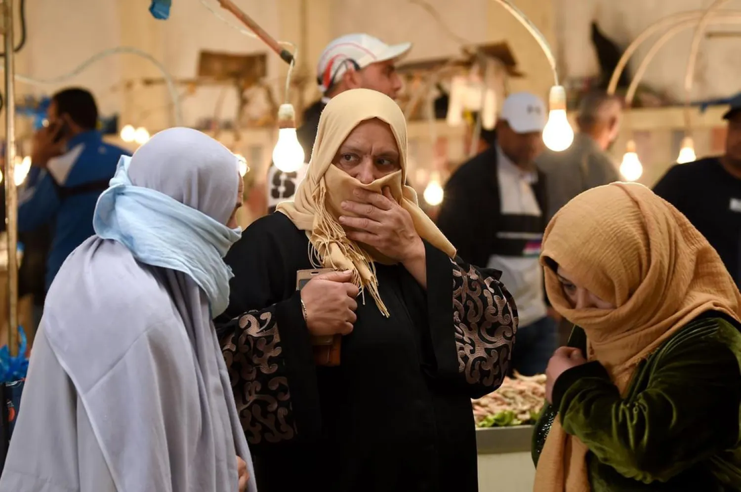 Tunisian women walk past stalls in a central market in the capital Tunis on April 24, 2020, during the first day of Ramadan. (AFP)