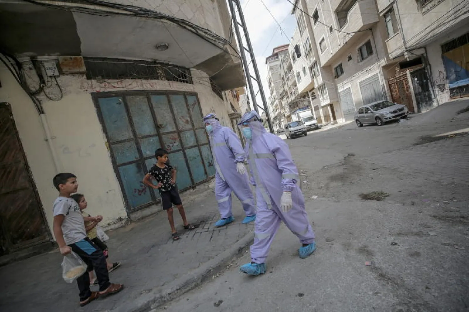 موظفان تابعان لوكالة الأمم المتحدة لإغاثة وتشغيل اللاجئين الفلسطين (الأونروا) يرتديان ملابس واقية خلال توزيع الأدوية في غزة (إ.ب.أ)