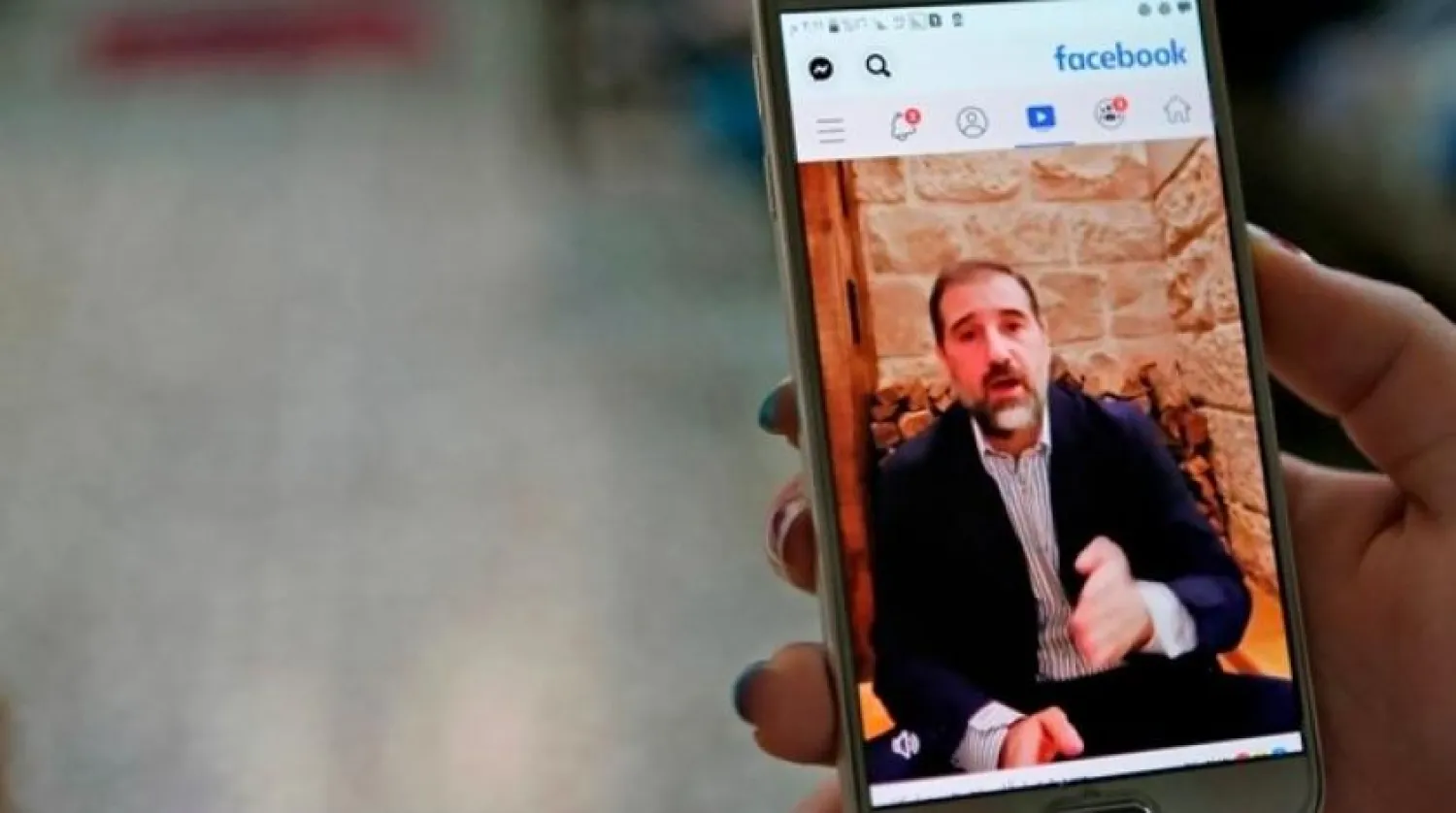A woman watches the Facebook video of Syrian businessman Rami Makhlouf on her mobile in Syria's capital Damascus, on May 11, 2020. Syria. AFP